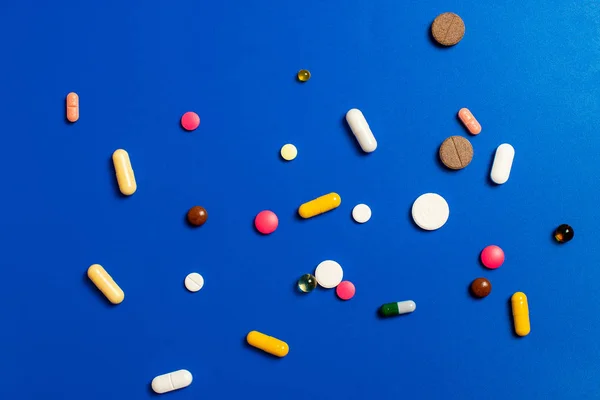 Primo piano di pillole multicolori assortiti su uno sfondo blu. Medico piatto laici . — Foto Stock