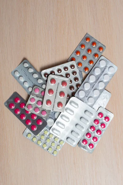 Blisters with multi-colored pills lie on a bright table. Medical flat lay.