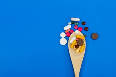 Etrafındaki tahta kutuda çok renkli haplar var. Mavi arka planda bir kopyalanma alanı. Tıbbi konsept