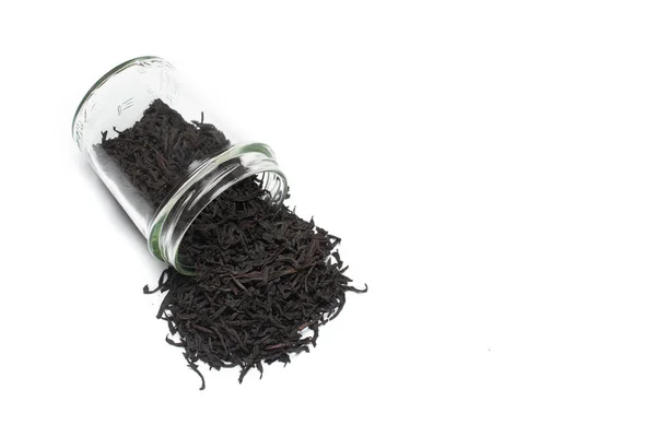 Glasburk med strödda stora blad svart te, isolerad på den vita bakgrunden — Stockfoto