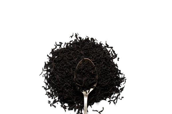 Löst blad svart te strös på en silversked och vit bakgrund. Utsikt ovanifrån. — Stockfoto