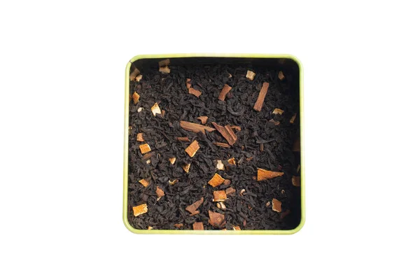 Hojas secas de té de fruta negra con canela y naranja en una lata. Aislar sobre un fondo blanco . — Foto de Stock