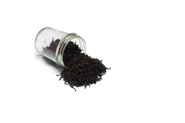 Tarro de vidrio con té negro de hoja grande espolvoreado, aislado sobre el fondo blanco —  Fotos de Stock