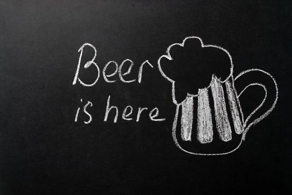 A pint of beer drawn by white chalk on a black chalkboard. The inscription "beer is here." Design beer menu for a restaurant or cafe. — Stock Photo, Image