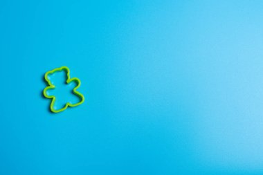 Mavi arka planda oyuncak ayı şeklinde kurabiye yapmak için yeşil plastik kurabiye makası. Mutfak konsepti. Kopyalama alanı ile düz uzandı.