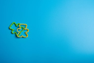 Mavi arka planda oyuncak ayı şeklinde kurabiye yapmak için yeşil ve sarı plastik kurabiye makası. Mutfak konsepti. Kopyalama alanı ile düz uzandı.