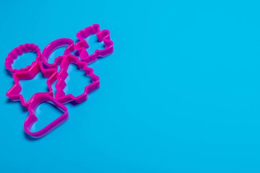 Pembe arka planda kurabiye yapmak için çeşitli şekillerdeki çok renkli plastik kalıplar. Mutfak konsepti. Kopyalama alanı ile düz uzandı.