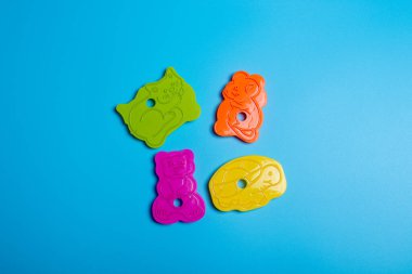 Mavi arka planda kurabiye yapmak için beş tane çok renkli plastik kurabiye makası. Mutfak konsepti. Kopyalama alanı ile düz uzandı.