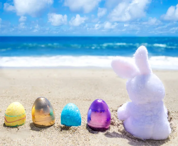 Easter bunny with color eggs on the ocean beach — Stock Photo, Image