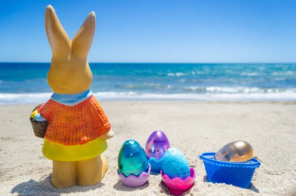 Easter bunny with color eggs on the ocean beach — Stock Photo, Image