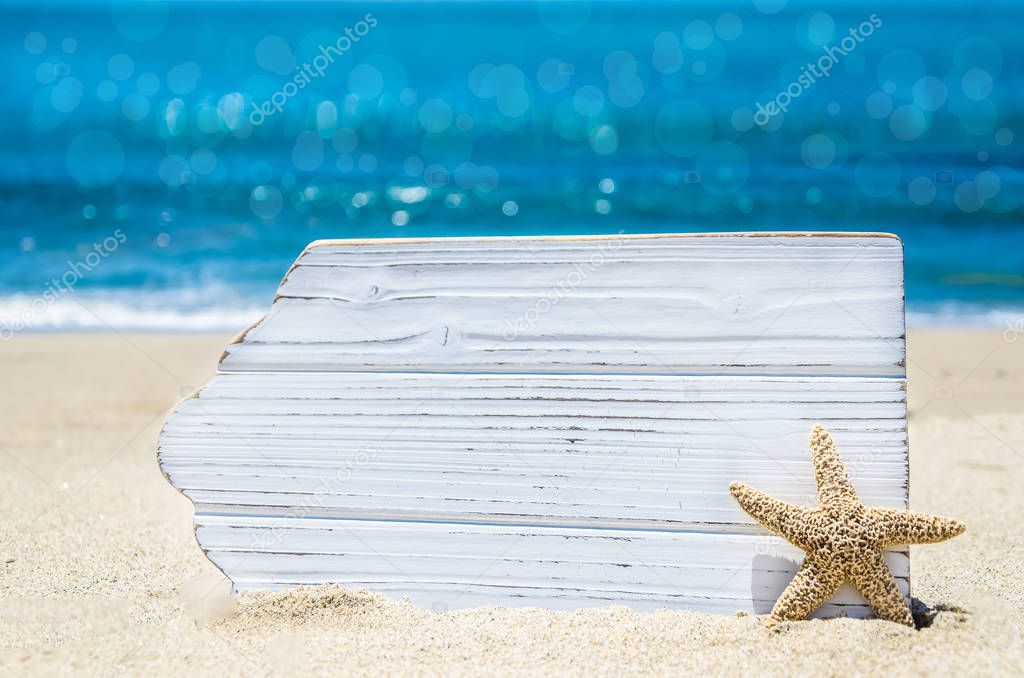 White wood board with starfish on the sandy beach