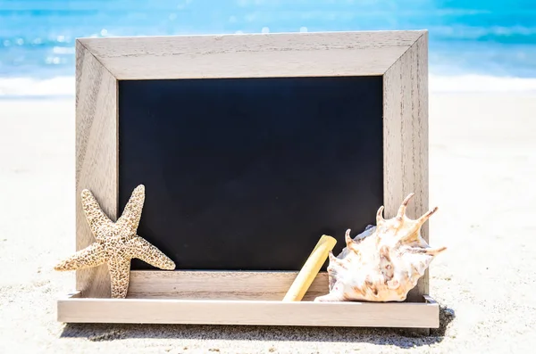Pizarra de madera negra con concha marina, estrella de mar y tiza en el s —  Fotos de Stock