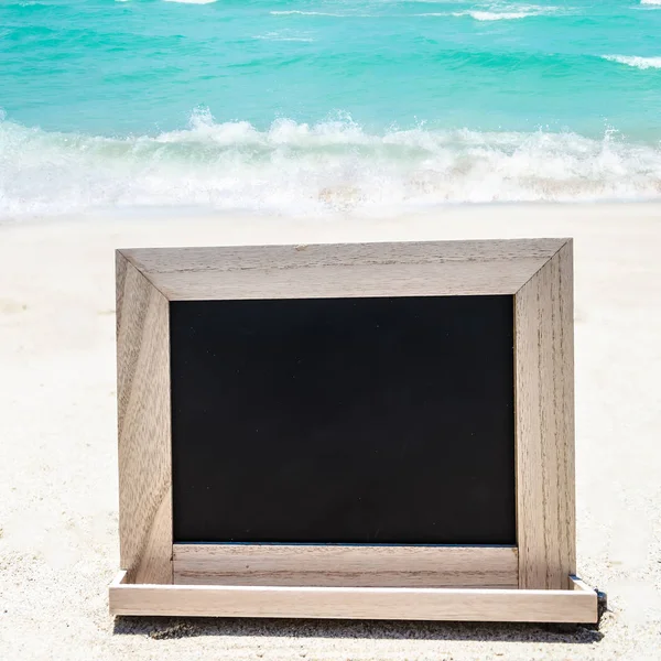 Lavagna in legno nero sulla spiaggia sabbiosa — Foto Stock