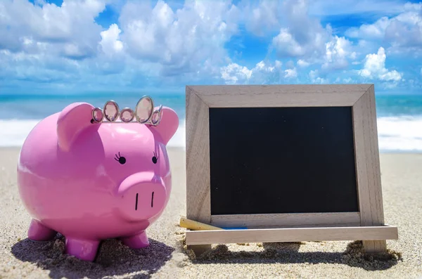 Banco Piggy e placa preta na praia — Fotografia de Stock