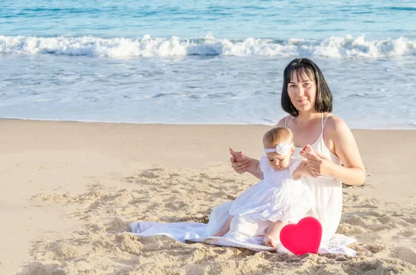 Matka s dcerou a srdce na písečné pláži — Stock fotografie