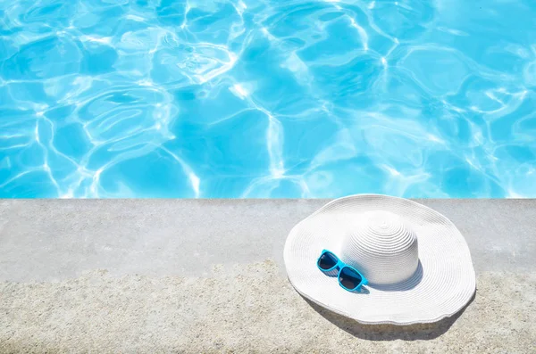 Sombrero de verano y gafas de sol cerca de la piscina — Foto de Stock