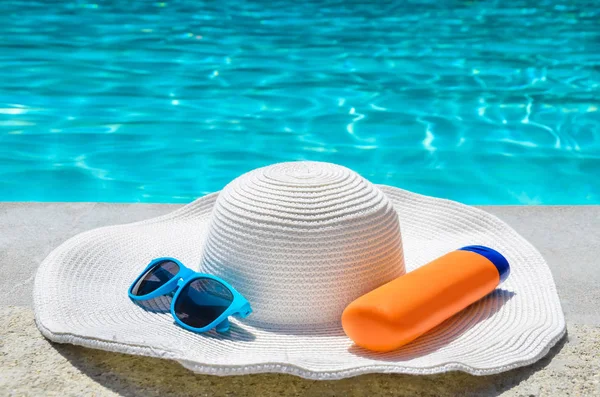 Sommaren hatt, solglasögon och solkräm nära poolen — Stockfoto