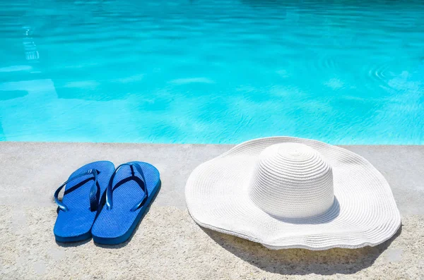 Sombrero de verano y chanclas cerca de la piscina —  Fotos de Stock