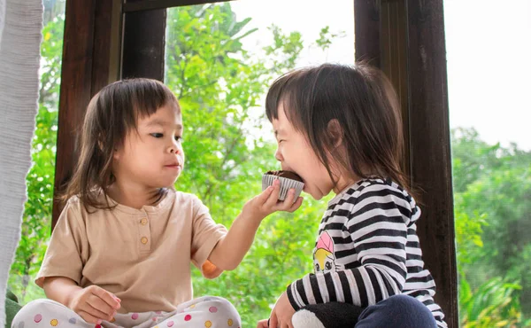 アジアの女の子と彼女の妹あります食べているバナナカップケーキでザ · 部屋おいしく. — ストック写真