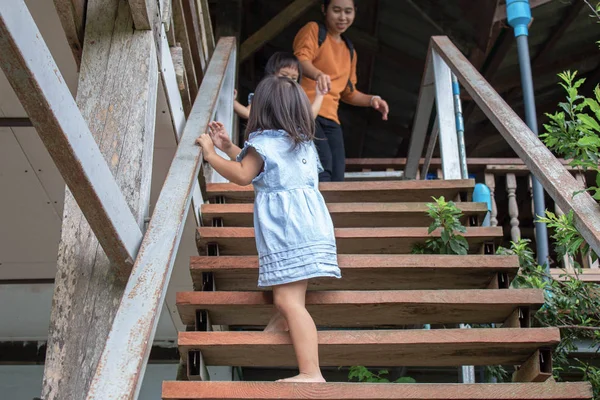 Niña asiática caminando por la escalera de madera en el restaurante. Peligroso en niños . — Foto de Stock