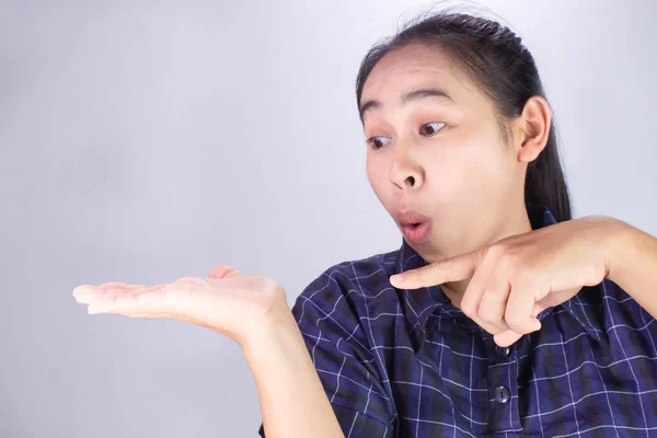 Close-up wow and surprised face of Asian young woman wearing blue shirt with hand point on empty space. — Stock Photo, Image