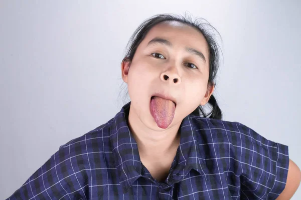 Mujer joven asiática en camisa azul, Hacer caras divertidas y mostrando la lengua larga para que usted sea feliz y no estresado. Concepto de lenguaje corporal y estímulo . — Foto de Stock