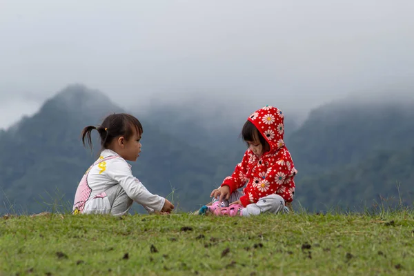 A menina asiática ajudou a colocar sapatos na irmã na grama na montanha Ang Khang, Fang Chiang Mai. Atração turística no norte da Tailândia . — Fotografia de Stock