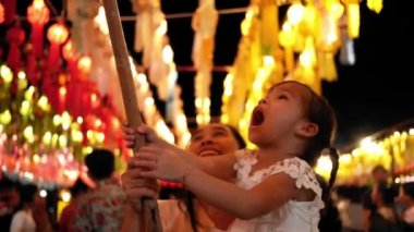 Lamphun 'daki Cham Devi avlusunda Yi Peng Festivali' nde dilek tutmak için Tayland lanna feneri asan mutlu bir Asyalı aile..