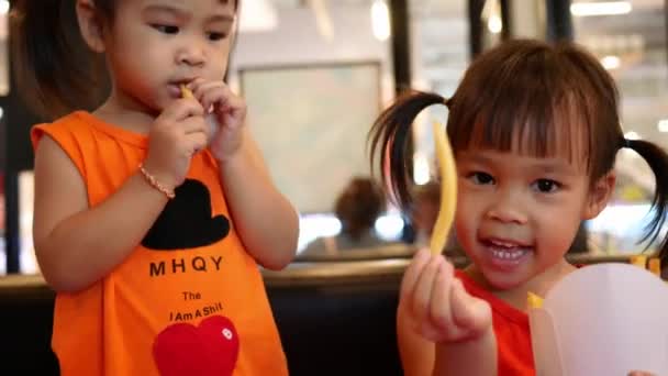 Glückliche Kleine Asiatische Mädchen Essen Pommes Mit Ihrer Schwester Restaurant — Stockvideo