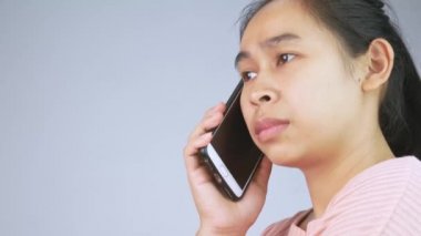 Beyaz arka planda izole edilmiş cep telefonuyla konuşan kızgın Asyalı genç kadın..