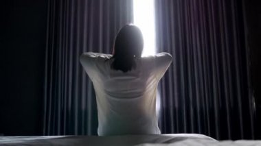 Parlak bir sabahta yatak odasında tembel tembel oturan Asyalı bir kadının arkası. Sağlık hizmeti kavramı.