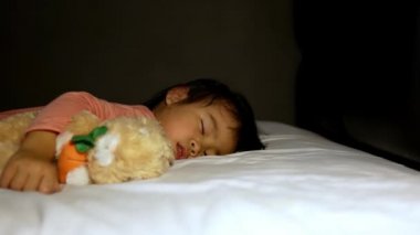 Asyalı anne yatakta uyuyan kızına battaniye örtüyor ve sevgiyle iyi geceler öpücüğü veriyor. Sağlık hizmeti kavramı.