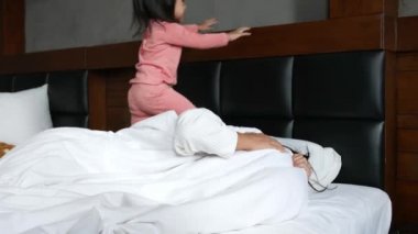 Sevimli Asyalı küçük kız sabahları annesini yatakta yatarken uyandırıyor..