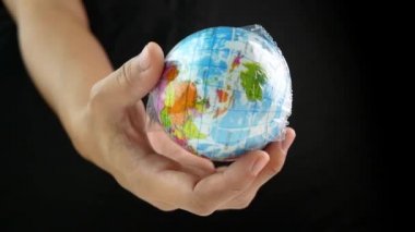 Kadın eli, dünyayı siyah arka planda plastik torba içinde tutuyor. Plastik molozların yol açtığı kirlilik nedeniyle küresel ısınma. Dünya Günü konsepti. 