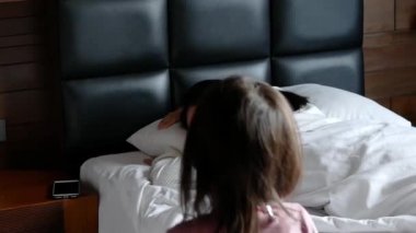 Sevimli Asyalı küçük kız sabahları annesini yatakta yatarken uyandırıyor..