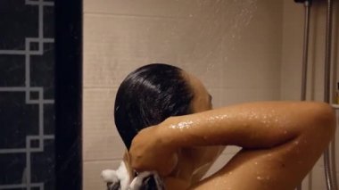 Genç, mutlu bir kadın duş alıyor saçlarını yıkıyor, tavandan düşen suyun altında duruyor evdeki yağmur duş başlığından düşüyor. Hijyen ve Sağlık Hizmetleri kavramı.