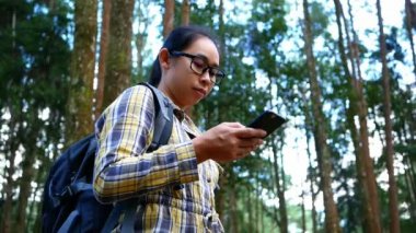 Genç bayan gezgin kayanın üzerinde oturuyor ve yaz tatillerinde Inthanon Dağı 'nın zirvesinde tablet tablet üzerindeki GPS koordinatlarını araştırıyor. Yaşam tarzı yürüyüşü kavramı.