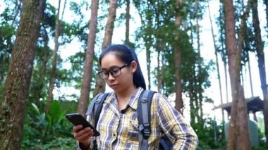Genç bayan gezgin kayanın üzerinde oturuyor ve yaz tatillerinde Inthanon Dağı 'nın zirvesinde tablet tablet üzerindeki GPS koordinatlarını araştırıyor. Yaşam tarzı yürüyüşü kavramı.