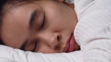 Yatakta yumuşak beyaz yastıkta horlayan Asyalı genç bir kadın. Sağlık hizmeti kavramı.