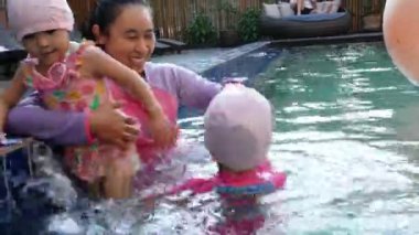 Mutlu Asyalı aile tatil beldesindeki yüzme havuzunda tatilin tadını çıkarıyor..