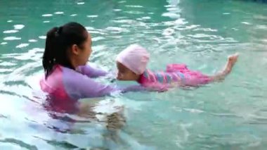 Anneden yüzme dersi alan Asyalı küçük kız yaz tatilinde havuzda kendine iyi bak..