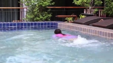 Mutlu Asyalı kadın tatil köyündeki yüzme havuzunda tatilin tadını çıkarıyor..