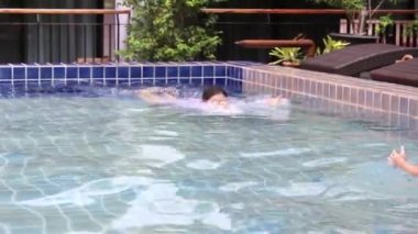 Mutlu Asyalı aile tatil beldesindeki yüzme havuzunda tatilin tadını çıkarıyor..