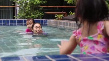 Mutlu Asyalı aile tatil beldesindeki yüzme havuzunda tatilin tadını çıkarıyor..