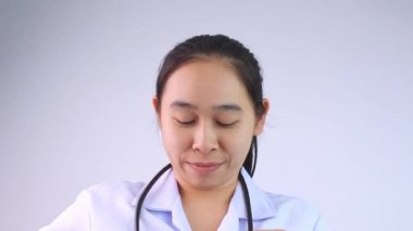 Güvenilir gülümseyen doktor steteskopunu tutarak beyaz arka planı kontrol etme zamanının geldiğini ima ediyor..