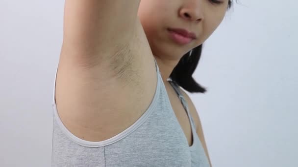 灰色の背景に孤立した無剃髪の脇の下と攻撃的な顔を示す若い女性のクローズアップ 肌と美しさのための健康管理の概念 — ストック動画