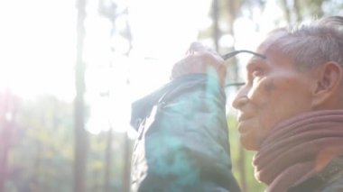 Mutlu Asyalı büyükbaba, soğuk mevsimde çam ormanlarında güneş ışığı eşliğinde doğanın manzarası üzerine bardak kaldırıyor..