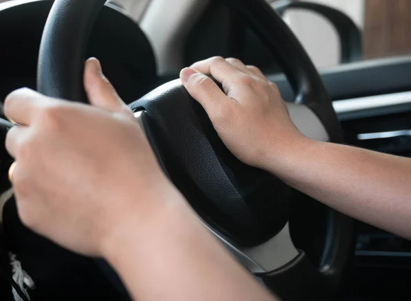 Close up inside vehicle of female hand pushing on steering wheel — Stock Photo, Image