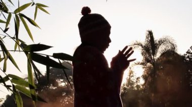 Mutlu güzel kadının silueti güneşin doğuşunda soğuk havanın tadını çıkarıyor..