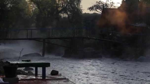 早朝には蒸気で自然の岩のビーチをゆっくりと流れる清らかな川の流れと川を渡る竹の橋の美しい景色 — ストック動画